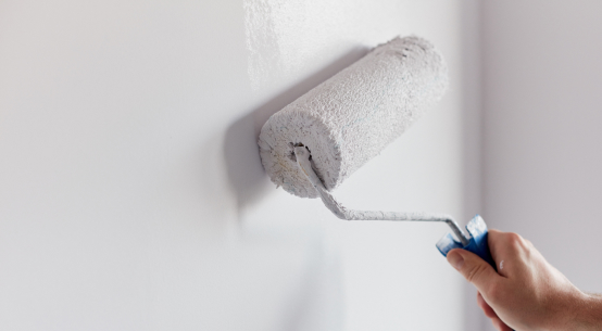 paint roller applying paint over newly installed drywall